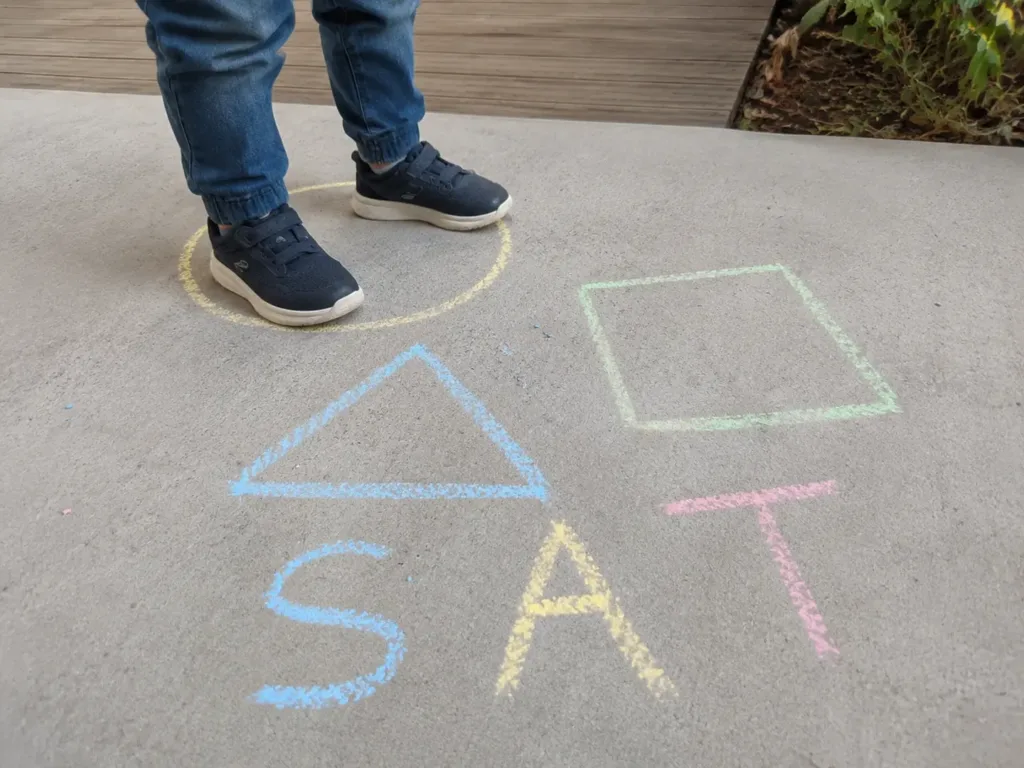 Colourful letters and shapes arranged as a movement path on outdoor pavement