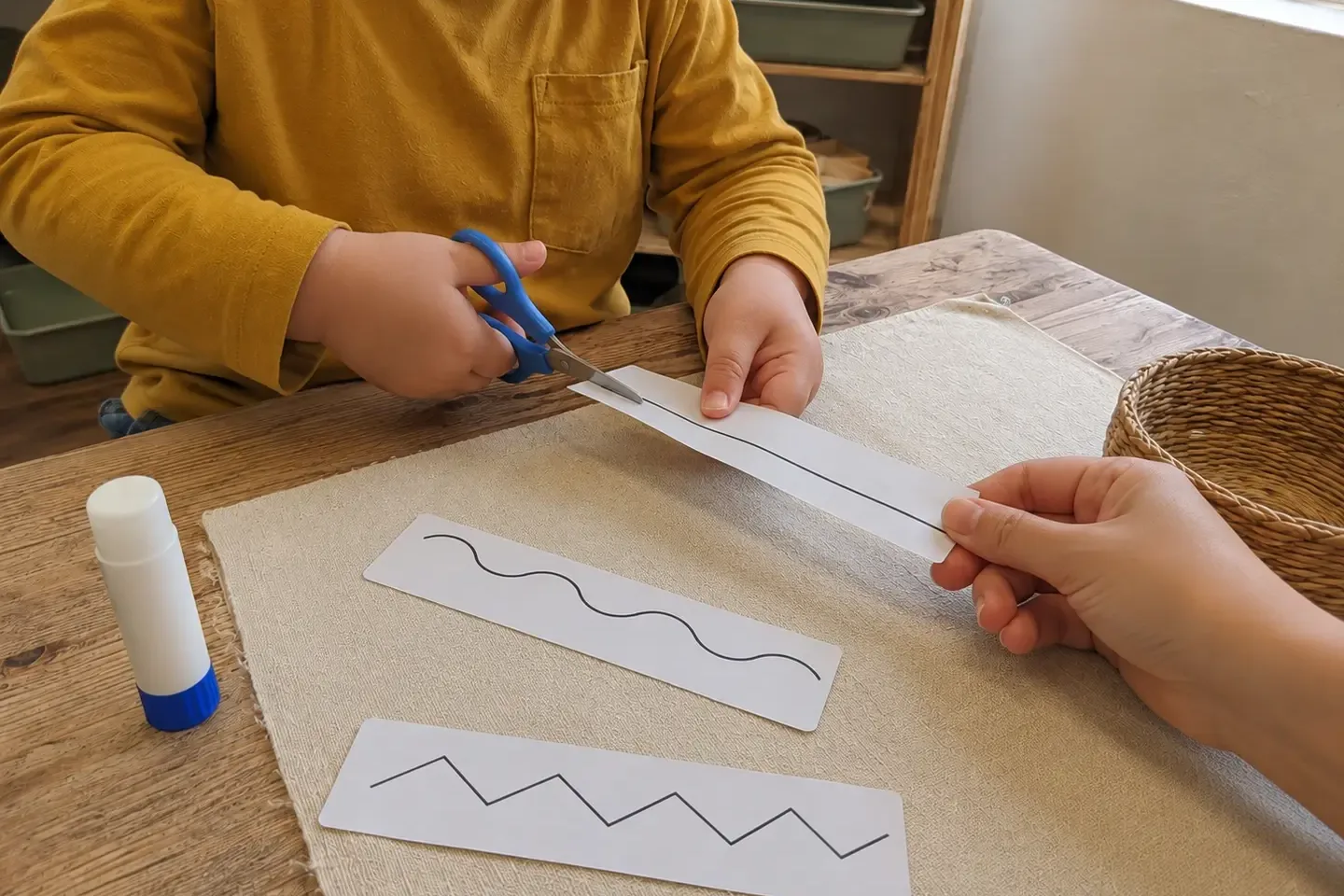 Preschool child practising cutting along a thick line with blunt-tip scissors