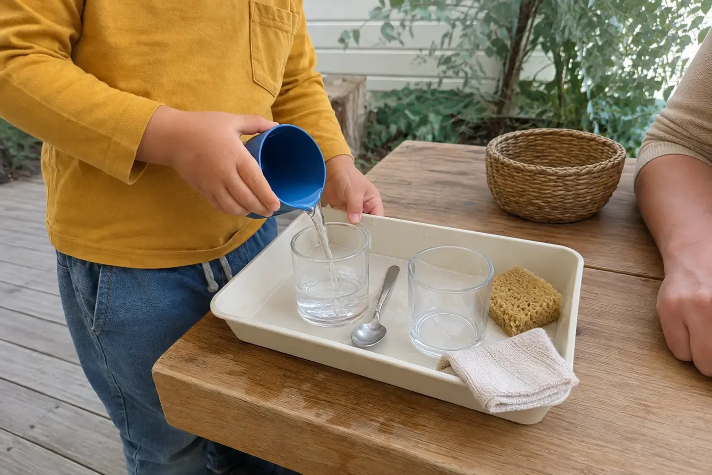 Preschool child carefully pouring water between containers during an outdoor sensory activity